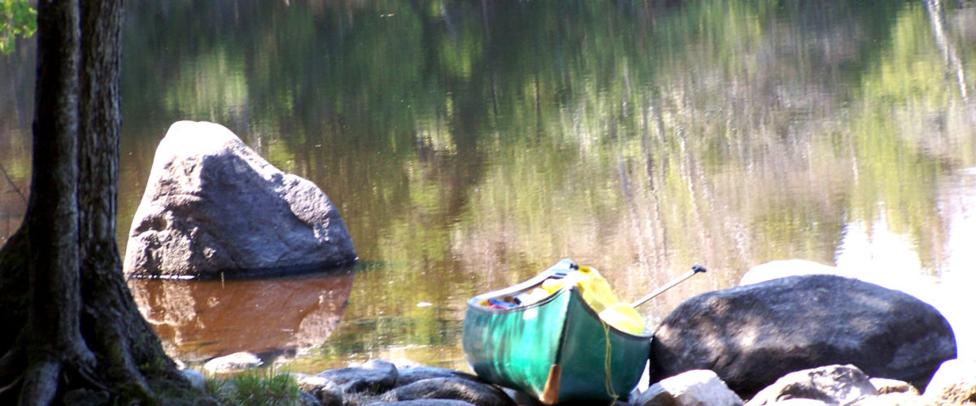Canoe leaning against a large rock on the shore of the American Cove. 