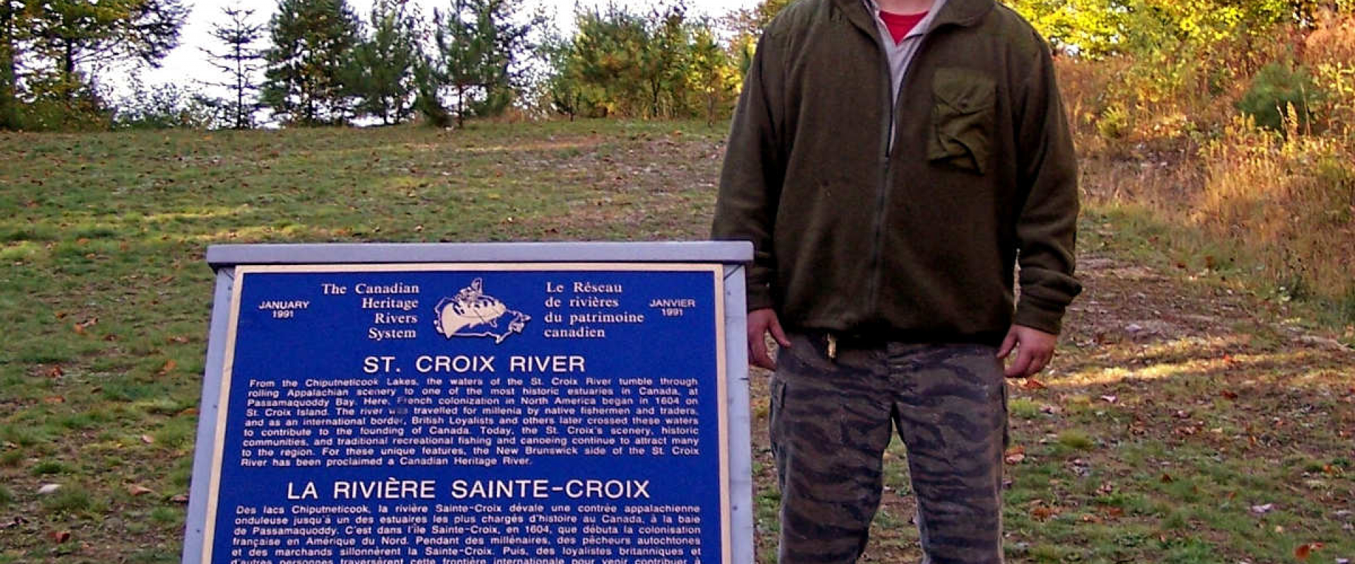 A man standing next to the Canadian Heritage Rivers System plaque commemorating the St. Croix River.