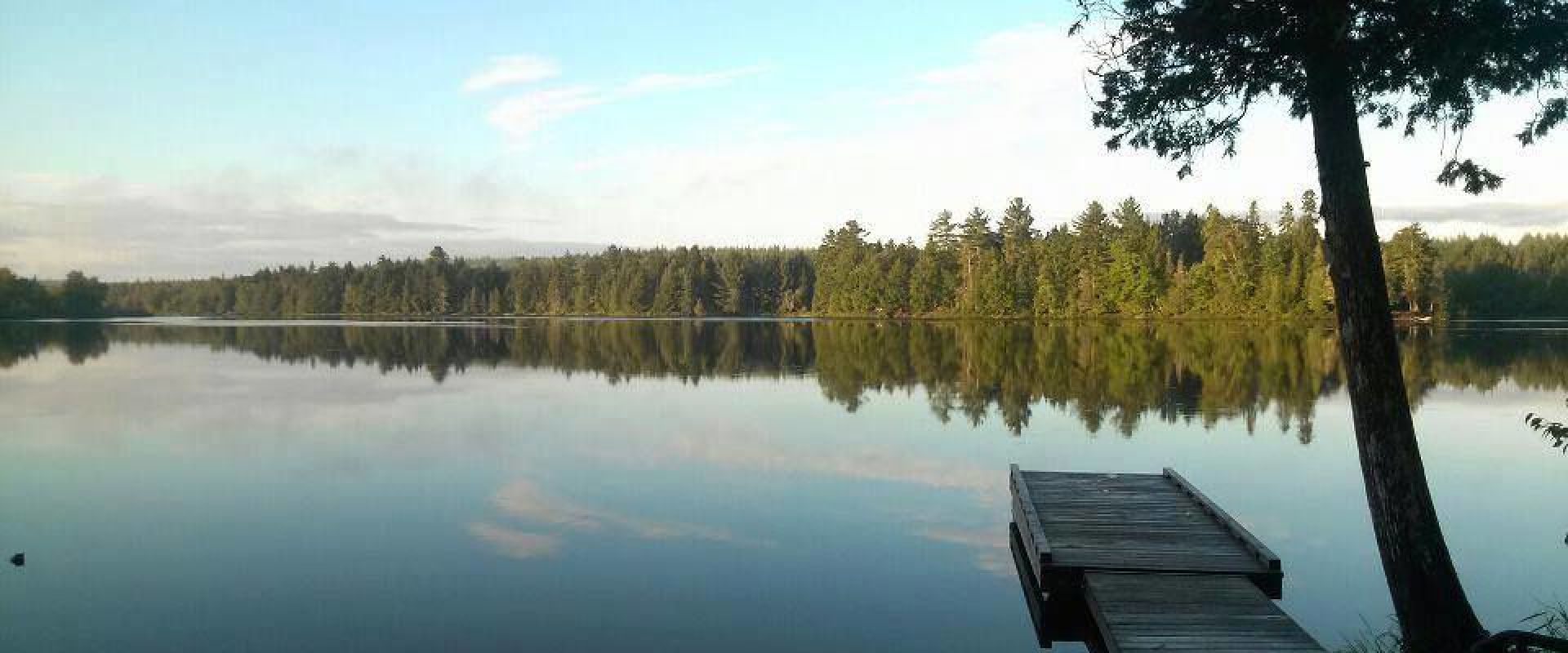 A dock floats on the calm waters of Loon Bay. The water displays a nearly perfect reflection