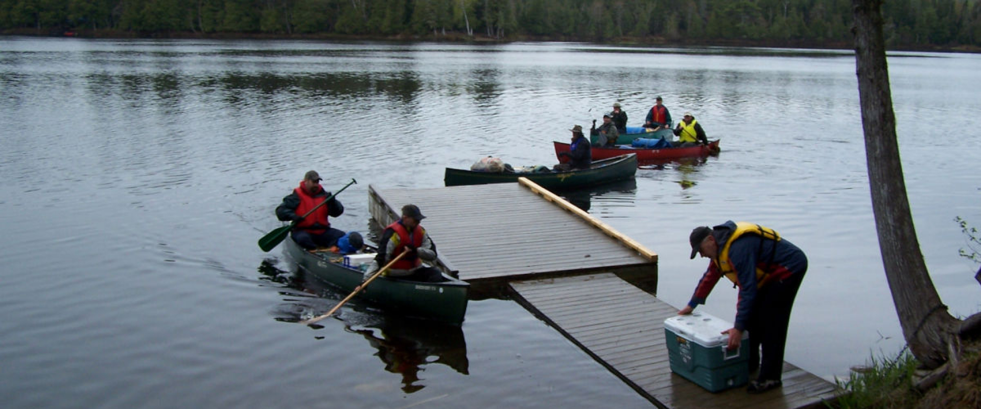 Canoeists dock their canoes at  the Loon Bay launch while others paddle nearby on the water. 