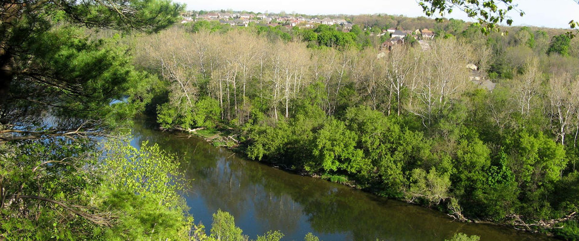 The Thames River flows by Komoka Bluff, with a town in the distance.