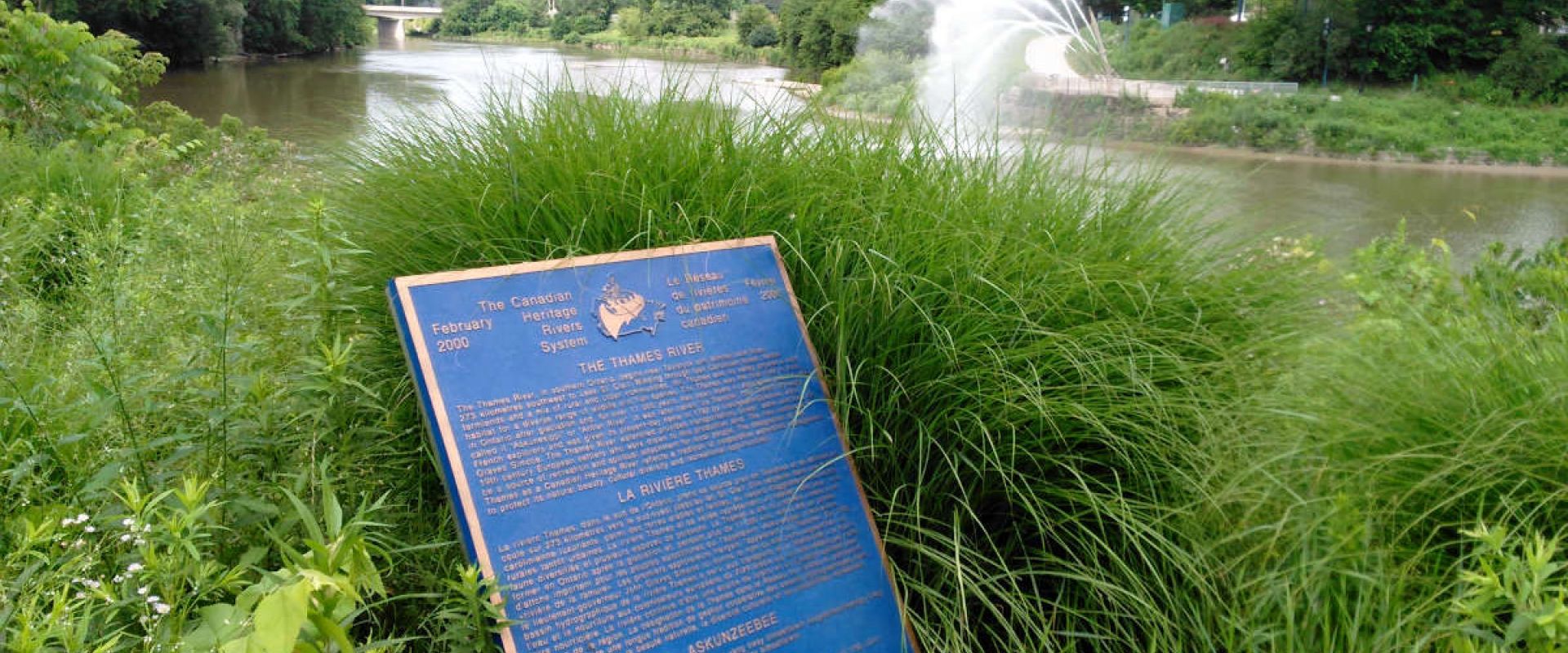 A Canadian Heritage Rivers System bronze plaque installed in a garden at the edge of the Thames River.