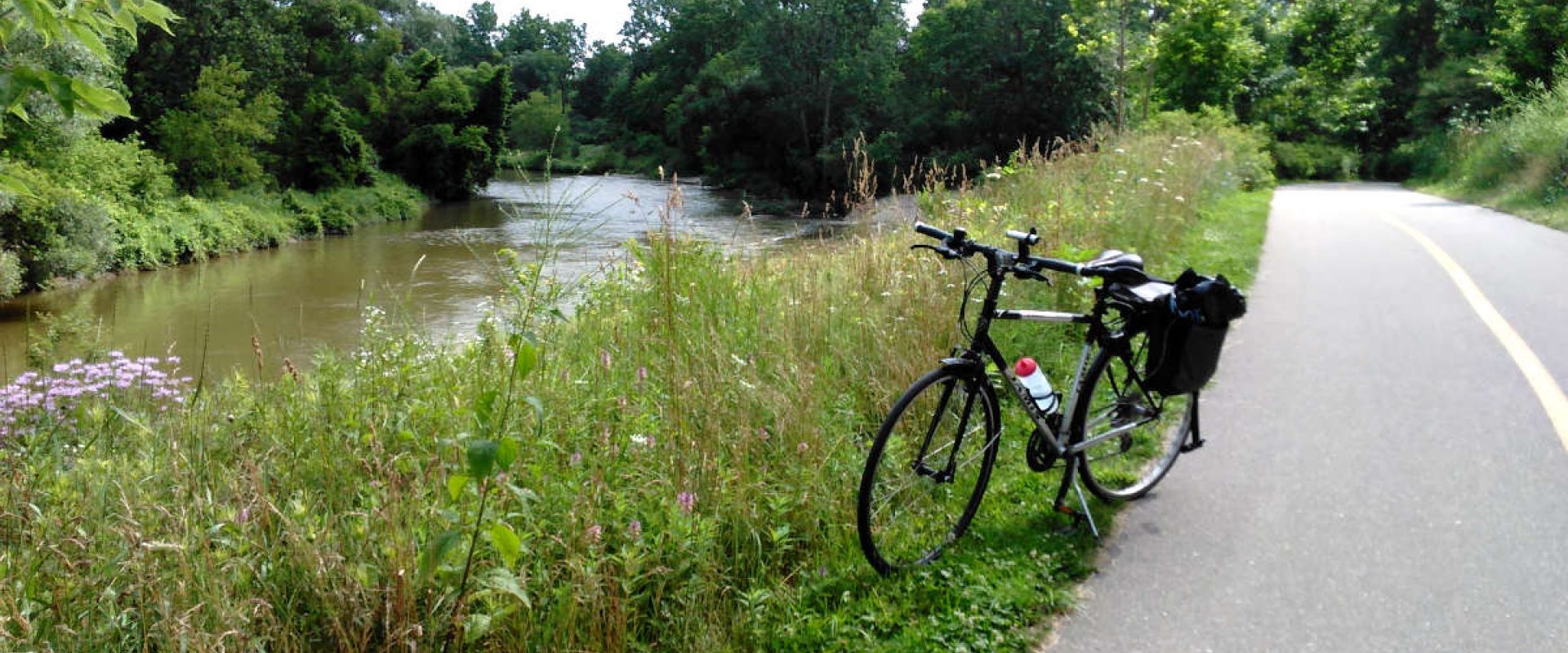 The Thames Valley Parkway is a paved 2-lane pathway available for walking, running, biking, and more. A bicycle is parked alongside the Thames River.
