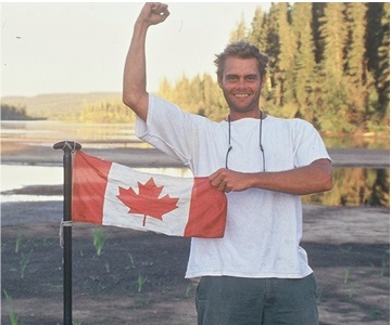 Young Canadian man proudly holding the Canadian Flag at Clearwater River, Alberta