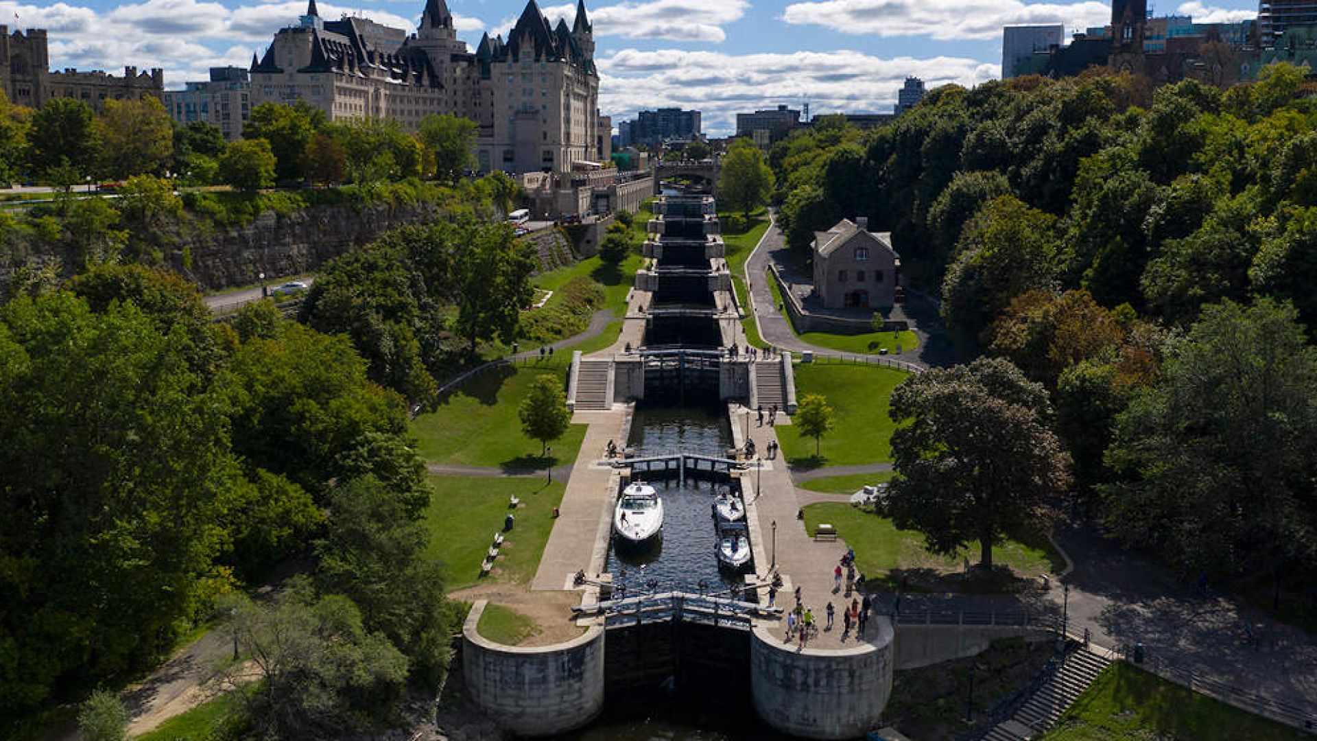 Boaters locking through the Ottawa Locks on a summer day. The Chateau Laurier is seen in the distance.
