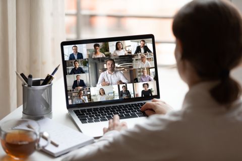 Vue par-dessus l'épaule d'un écran d'ordinateur montrant une vidéoconférence.