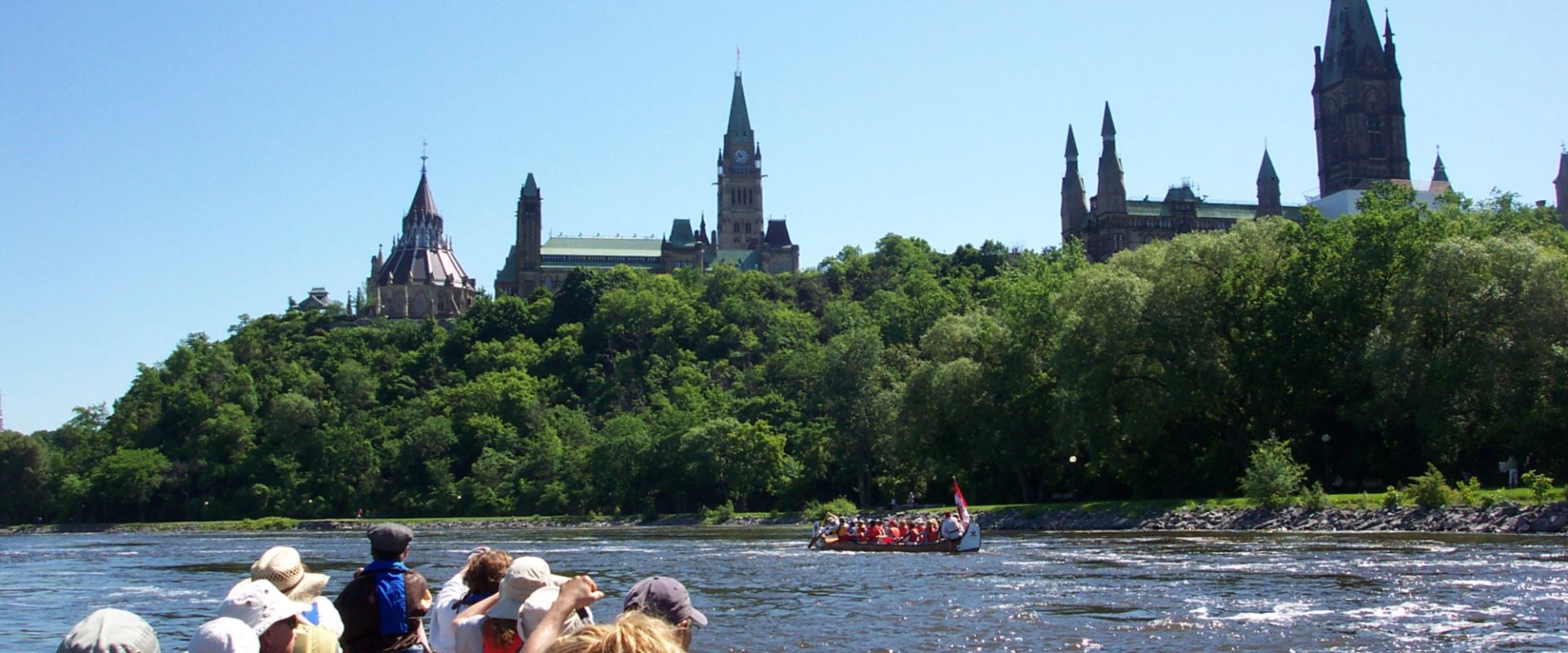Un groupe de pagayeurs fait la fête sur la rivière des Outaouais, devant la colline du Parlement.